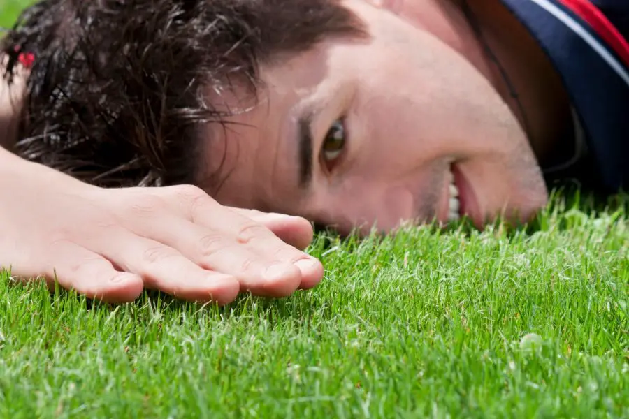 Mężczyzna dotykający idealnie ściętej trawy nożycami akumulatorowymi